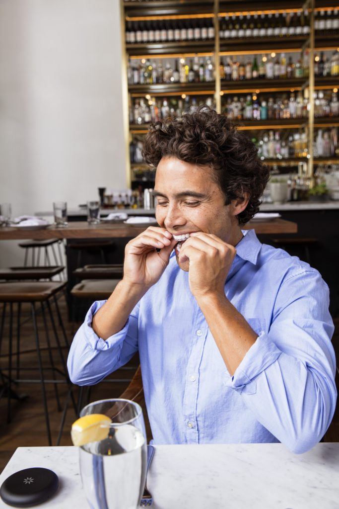 Man putting Invisalign in his mouth